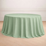 Round mint green tablecloth on a wooden floor.