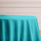 Turquoise tablecloth draped over a round table against a light background.