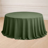 Round olive green tablecloth on a wooden floor.