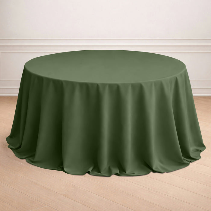 Round olive green tablecloth on a wooden floor.