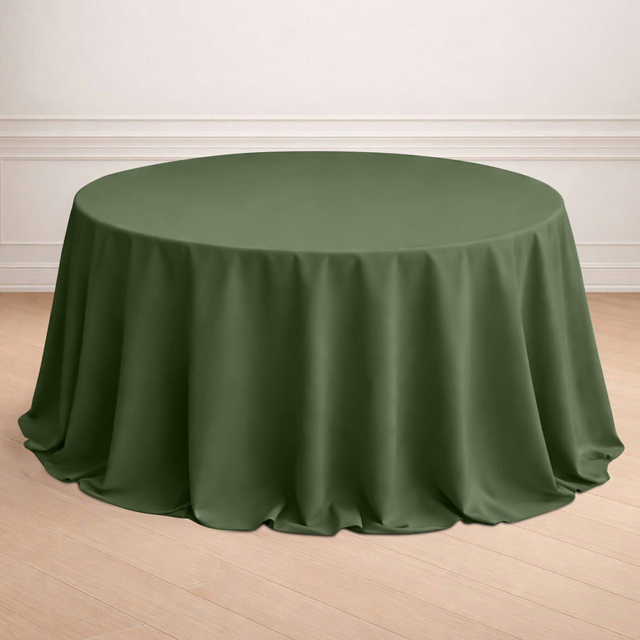Round olive green tablecloth on a wooden floor.