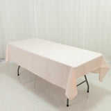 Pink tablecloth draped over a folding table on a plain backdrop.