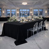 Elegant black dining table set with candles and flowers in a sophisticated venue.