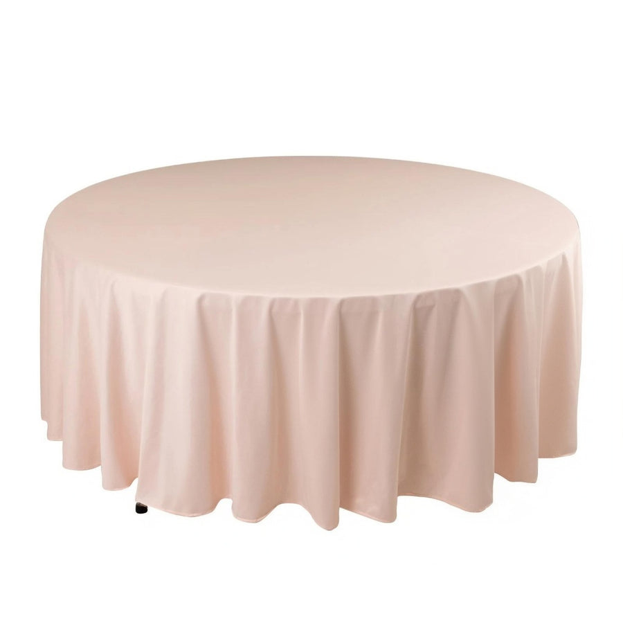 Round pink tablecloth with elegant draping on a plain backdrop.