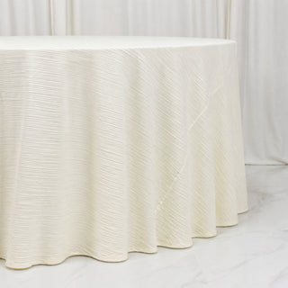 Elegant white textured round table with draped fabric skirt on marble floor