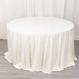 Round white table with a draped tablecloth in a studio setting.