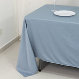 Blue tablecloth draped over a table with a white plate and glass on top.