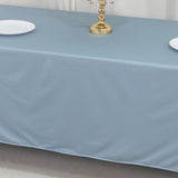 Elegant light blue tablecloth with gold candle holder and white plates.
