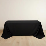 Black tablecloth draped over a table on a light wooden floor.