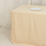 Beige tablecloth draping over a table with a white plate on top.