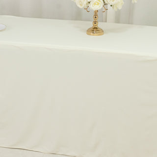 Elegant cream tablecloth draped over a table with a golden candle holder and flowers.