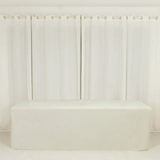 White table cover on a plain table with sheer white curtains in the background.