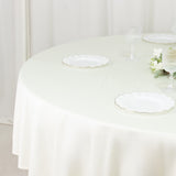 Elegant round table set with white scalloped plates and decorative flowers.