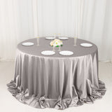 Elegant round table with a gray satin tablecloth and white plates for special occasions.
