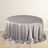 Silver round tablecloth with elegant draping on a wooden floor.