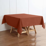 Rust-colored tablecloth draped over a wooden table in a staged setting.