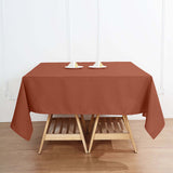 Brown tablecloth draped over a wooden table with candle holders on top.