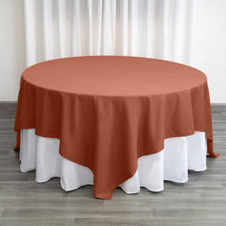 Round terracotta tablecloth draped over a white table.