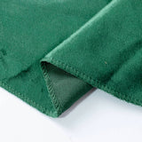 Green velvet fabric texture close-up with stitched hem and folded edge