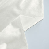 Close-up of white stitched fabric corner on a light blue background