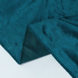 Teal velvet fabric close-up with folded edge and textured backing