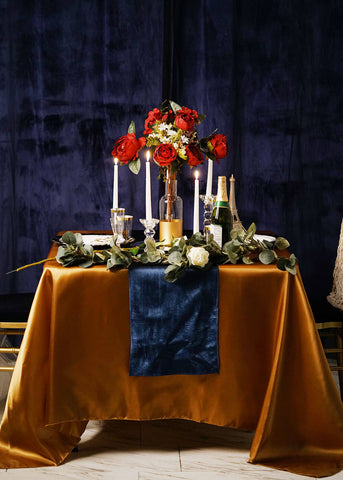 Gold tablecloth with navy runner and red floral centerpiece