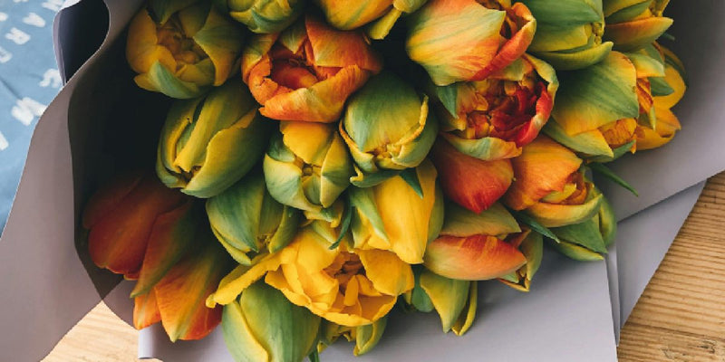 Artificial yellow and orange flowers on a wooden surface
