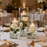 Elegant floral centerpieces with floating candles and roses at a dining table.
