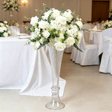 Elegant white wedding floral centerpiece in tall glass vase at reception table