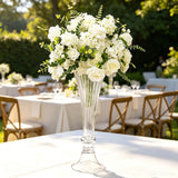 Elegant white floral centerpiece in tall glass vase at outdoor wedding reception