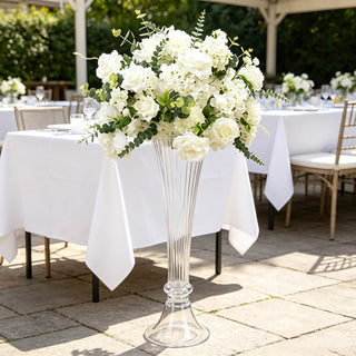 Elegant white wedding centerpiece in a tall glass vase outdoors
