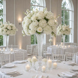 Elegant white floral wedding centerpiece on a banquet table in a bright reception hall
