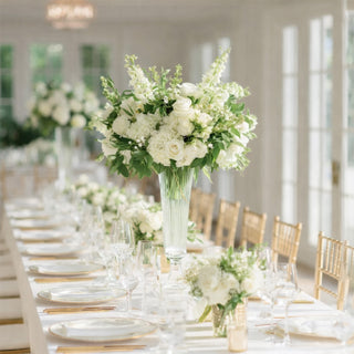 Elegant floral arrangement with white roses and greenery on a beautifully set dining table.