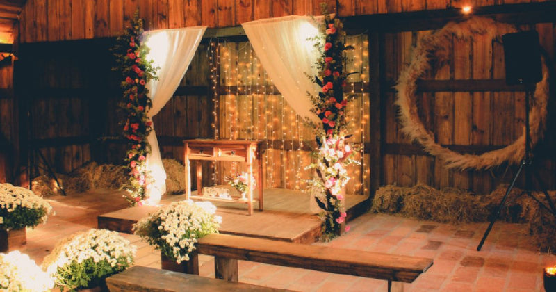 Rustic barn wedding stage with draped arch and lights
