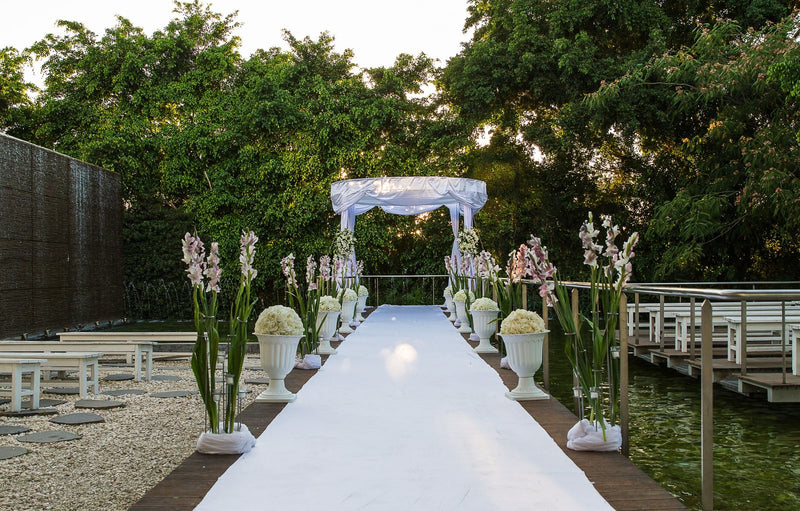 Outdoor wedding aisle with white draping and floral arrangements