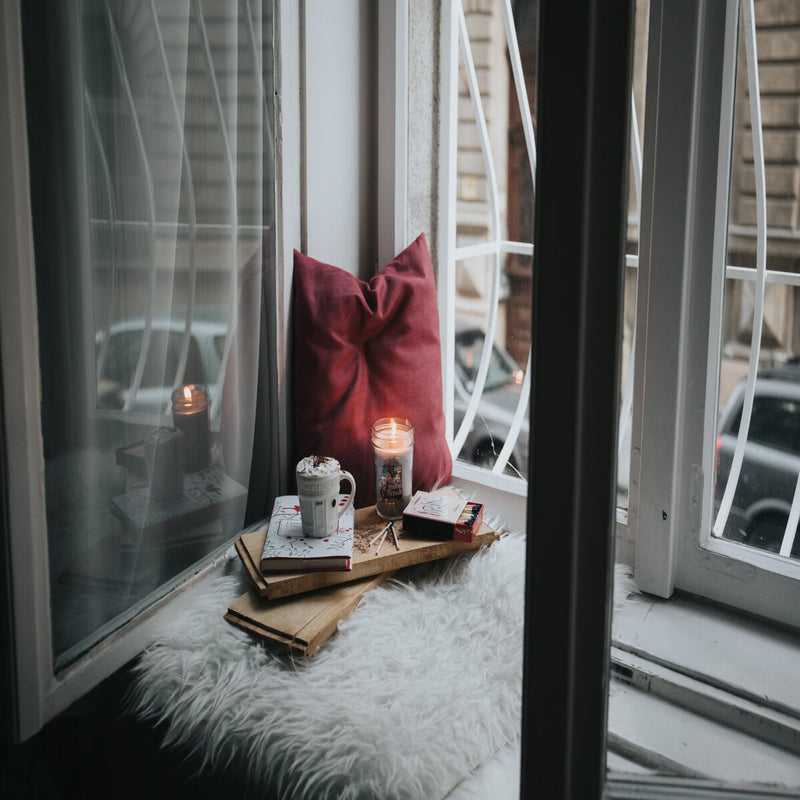 White sheepskin rug in a window seat with books and candle