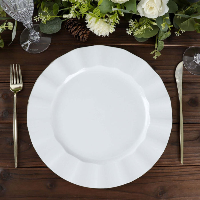 Elegant white scalloped dinner plate with silver cutlery on a wooden table.