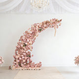 Floral installation arch in soft pink hues against a plain backdrop.