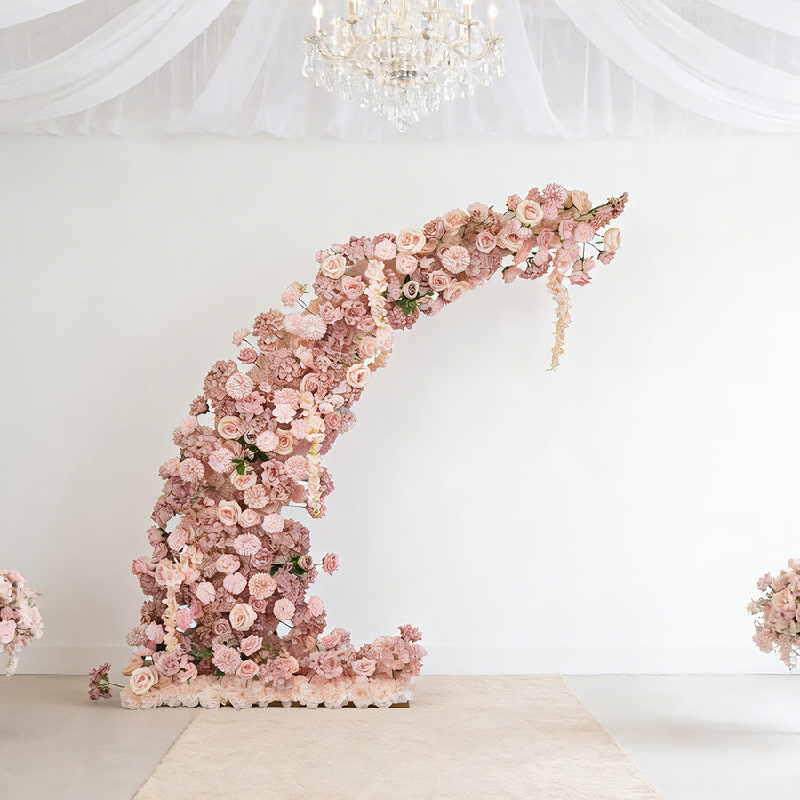 Floral installation arch in soft pink hues against a plain backdrop.