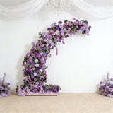 Purple floral arrangement arch with roses and flowers in a staged setting.