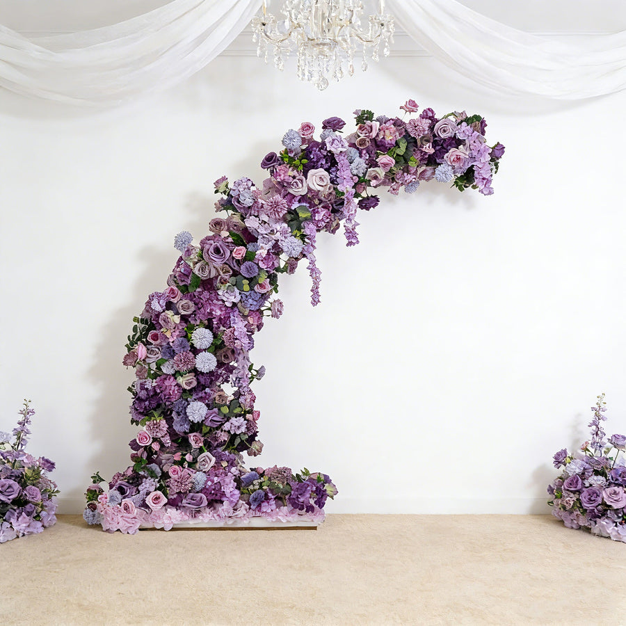 Purple floral arrangement arch with roses and flowers in a staged setting.