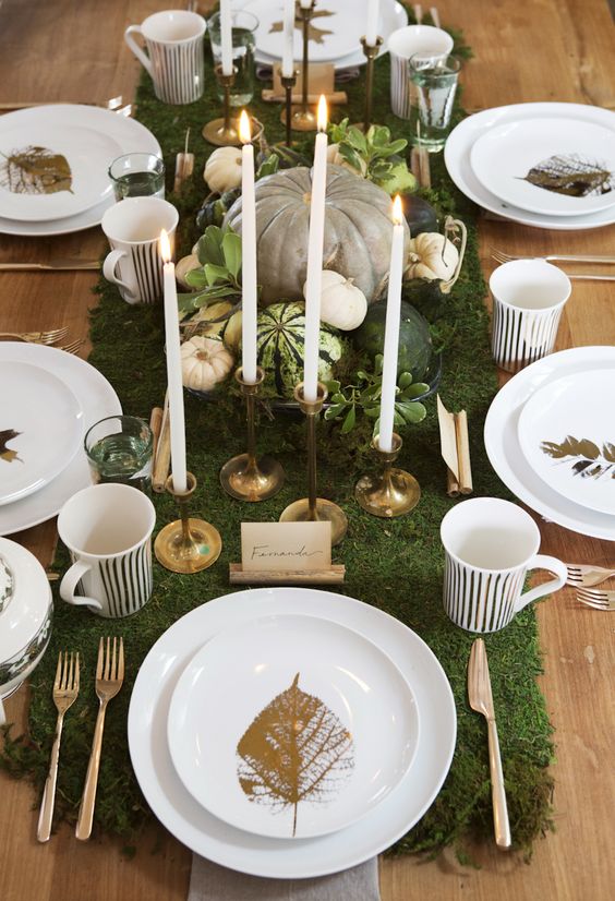 Thanksgiving table with candles, greenery, and pumpkins