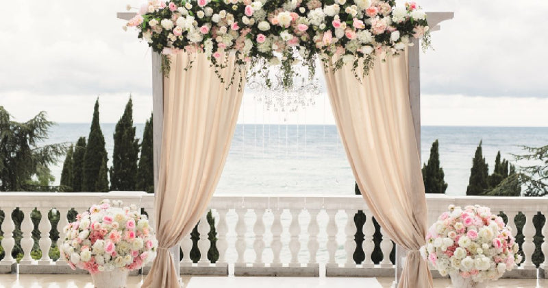 Flower-covered wedding arch with draped fabric
