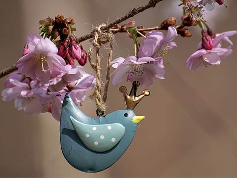 Blue bird ornament hanging from a flowering branch