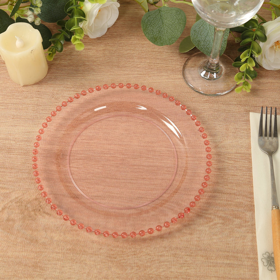 Pink decorative plate with beaded edge on a wooden table setting.