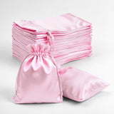 Pink satin drawstring bags stacked on a white background.