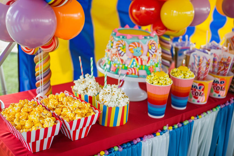 Colorful carnival-themed decor with popcorn and candy at a corporate event.