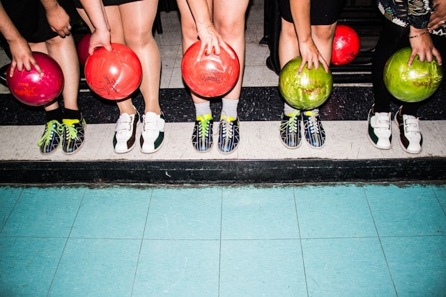 Group holding colorful bowling balls ready for a corporate holiday party outing.
