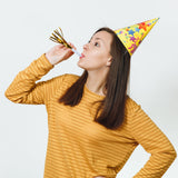 Woman in a party hat blowing a noisemaker, celebrating a special occasion.