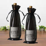 Dolcino wine bottles in elegant black gift bags on a wooden table.
